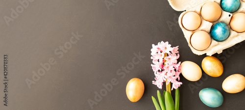 Easter eggs, flowers on dark background. Flat lay, top view, copy space. Easter day.