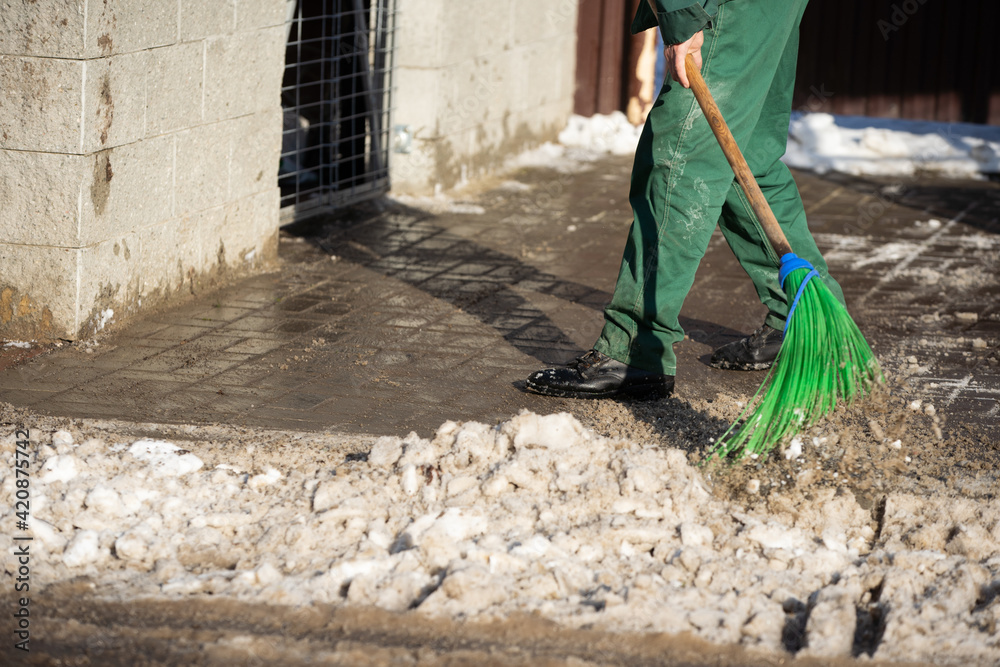 A close-up view as a worker sweeps the pavement out of loose snow A close-up view as a worker sweeps the pavement out of loose snow