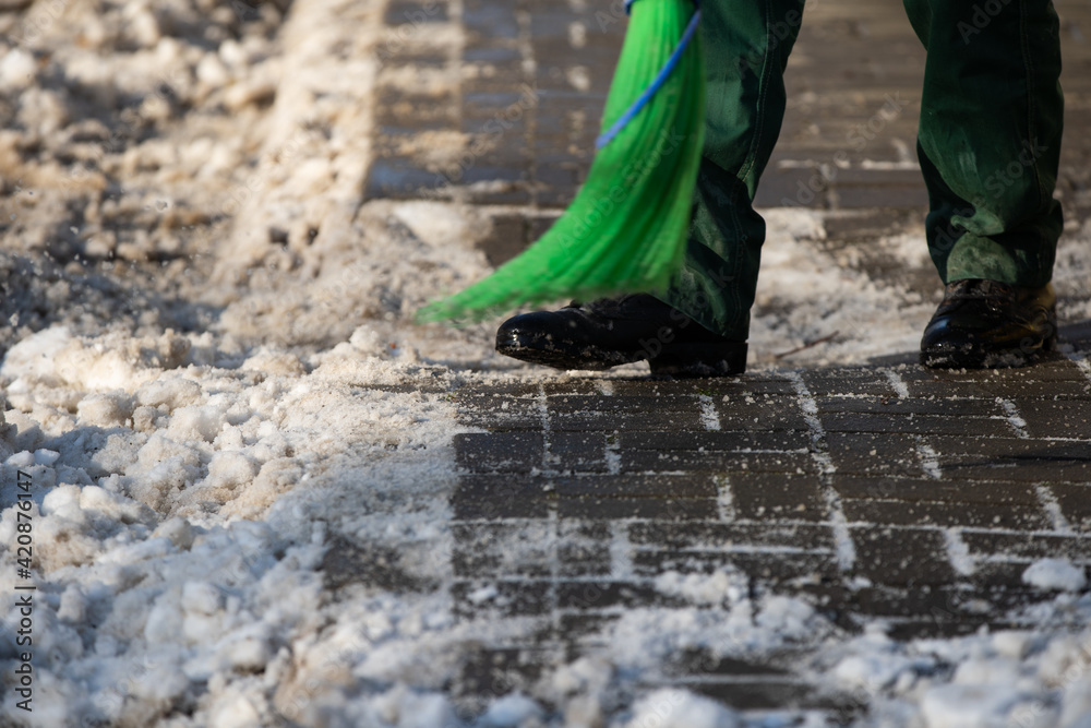 A close-up view as a worker sweeps the pavement out of loose snow A close-up view as a worker sweeps the pavement out of loose snow