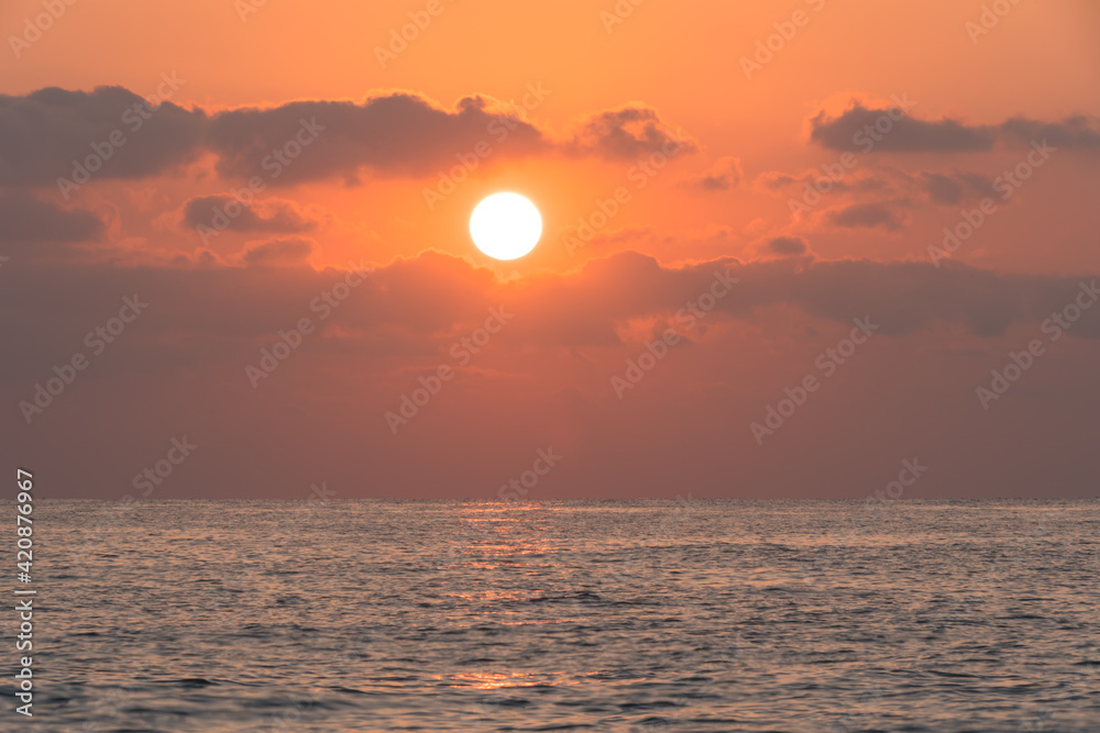 A sunrise scene over the Mediterranean sea when the sun is above some clouds
