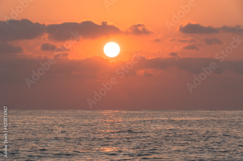A sunrise scene over the Mediterranean sea when the sun is above some clouds © Onur