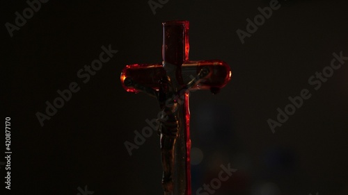 Close up of cross of jesus with blood lit by candle..