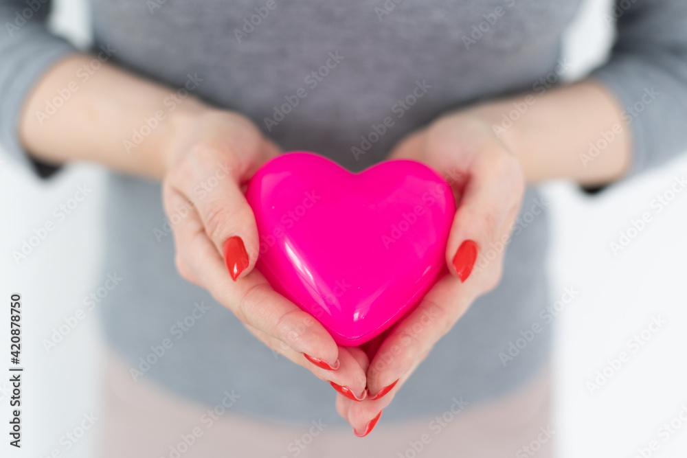 Young happy woman hold Love symbol red heart. Isolated on studio background female model. Young happy woman hold Love symbol red heart. Isolated on studio background female model.