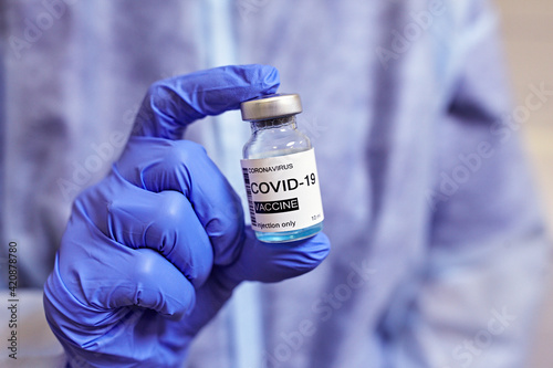 Hand in blue medical gloves holding covid-19 vaccine. Coronavirus covid 19 cure concept