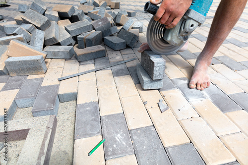 A worker cuts paving slabs with a grinder for subsequent laying.