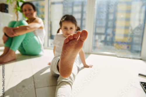 Focus on foot of a little girl exercising with her mom at home © Taras Grebinets