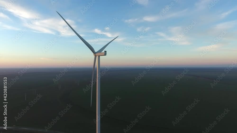 Aerial shot of one wind energy pillar with rotating vanes on seaside in summer Aerial shot of one wind energy pillar with rotating vanes on seaside in summer