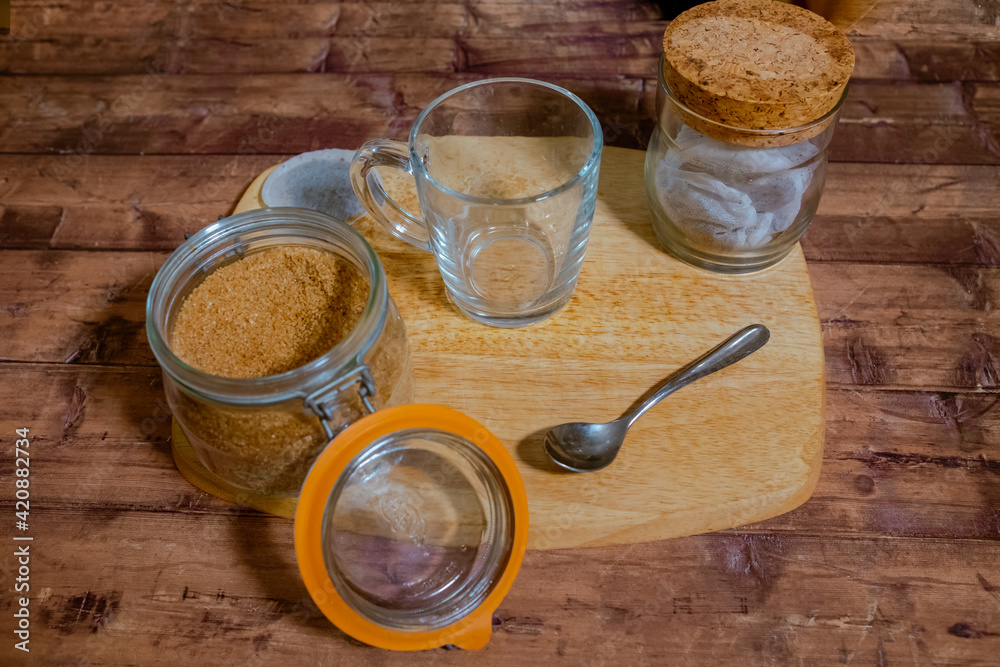 A cup of tea on a wooden chopping board with a brown sugar bowl next to it. A cup of tea on a wooden chopping board with a brown sugar bowl next to it.