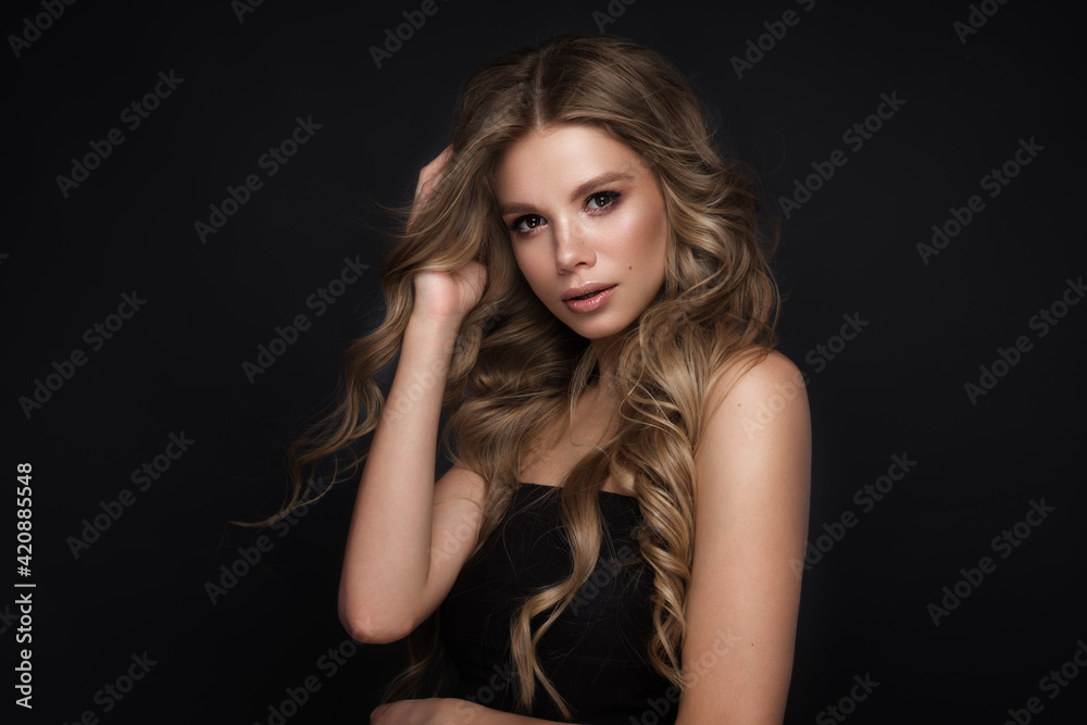 Beautiful blond girl with a perfectly curls hair, and classic make-up. Beauty face and hair.