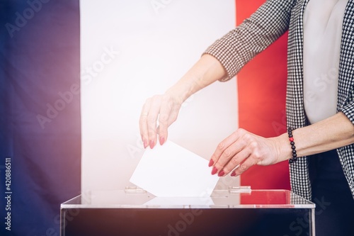 Elections in the country. Voting at the ballot box. A womans hand puts her vote into the ballot box.