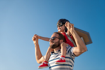 Father and son playing against blue summer sky background