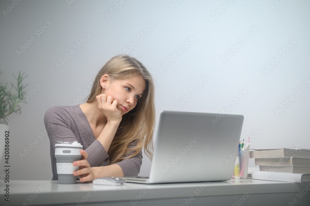 A girl with a laptop is studying at an online school. White room background A girl with a laptop is studying at an online school. White room background