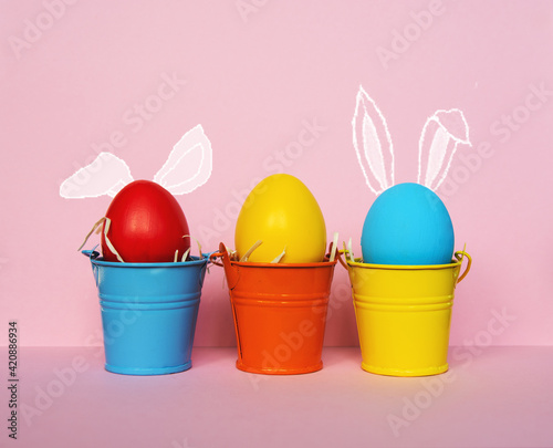 colored Easter eggs in bright buckets with rabbit ears, selective focus image. Happy Easter card.