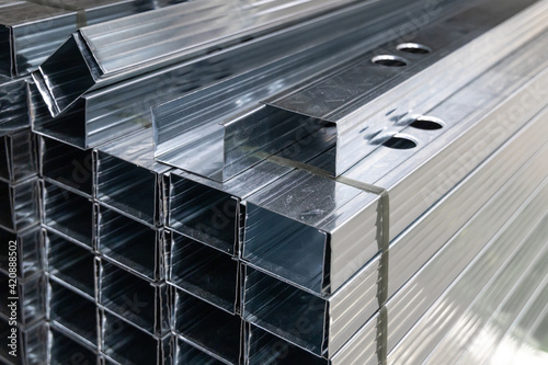 Rectangular aluminum profiles for hang drywall. Construction material for working with plasterboard and gypsum sheet. Stack of metal profiles in a warehouse