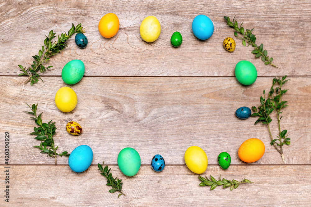 Colorful easter chicken and quail eggs frame with green plant branches on wooden rustic background with copy space, spring easter concept, top view Colorful easter chicken and quail eggs frame with green plant branches on wooden rustic background with copy space, spring easter concept, top view