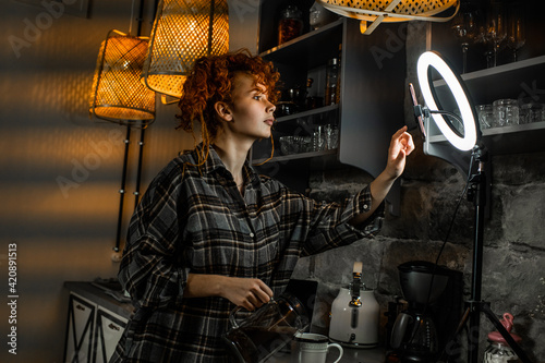 Female blogger with ring light and smartphone records video for social media in a kitchen. Blogger life.