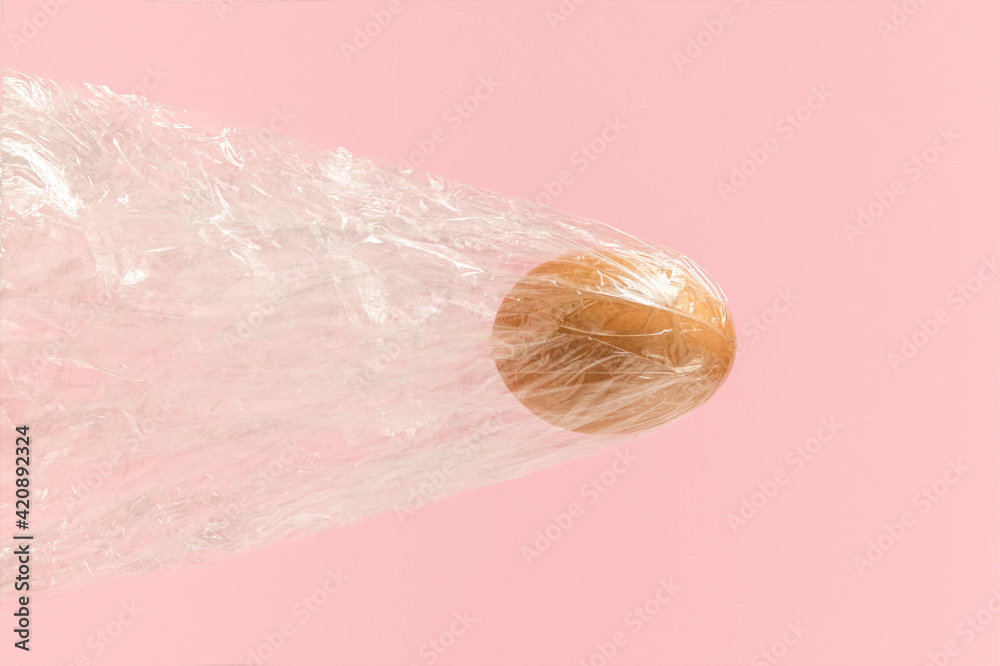 Fototapeta premium Natural Easter egg flying with foil bag on pink background. Bullet egg or airplane broke throught the sound barrier. Creative holiday concept.