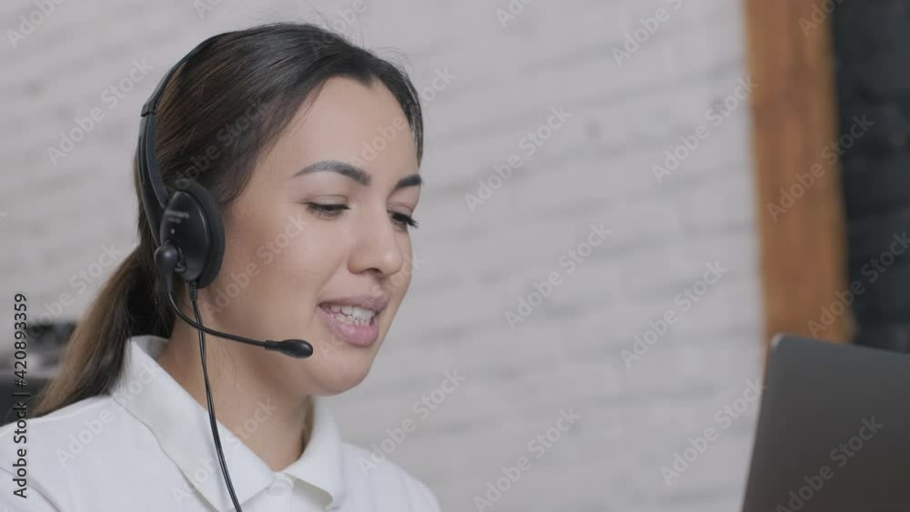 Smiling woman call centre operator, customer support agent wears headset consults client online typing on laptop, talk in internet computer chat, helpline operator secretary make conference video call Smiling woman call centre operator, customer support agent wears headset consults client online typing on laptop, talk in internet computer chat, helpline operator secretary make conference video call