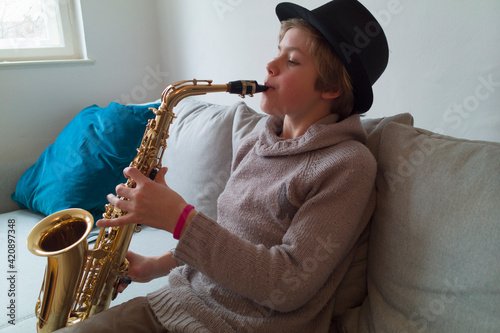 Boy practising saxophone on sofa photo
