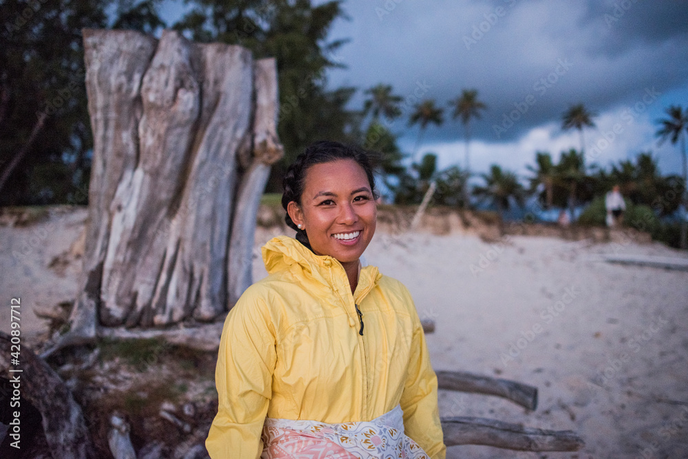 Woman relaxing by old tree trunk, Kailua Beach, Oahu, Hawaii Woman relaxing by old tree trunk, Kailua Beach, Oahu, Hawaii