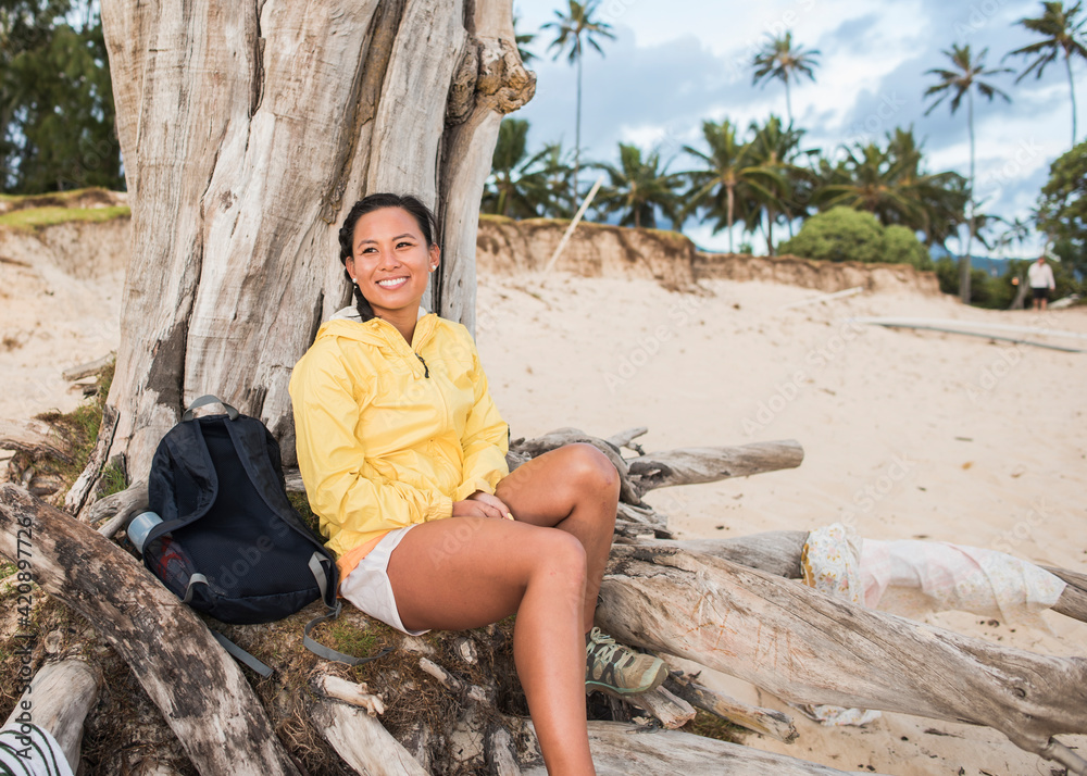 Woman relaxing by old tree trunk, Kailua Beach, Oahu, Hawaii Woman relaxing by old tree trunk, Kailua Beach, Oahu, Hawaii