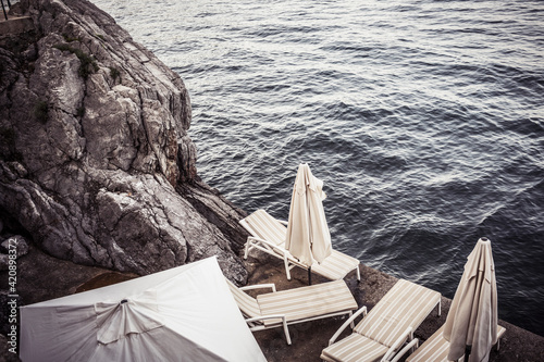 Empty sun loungers on rocky coast, high angle view, Lovran, Primorsko-Goranska, Croatia photo