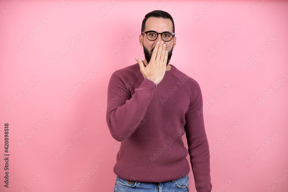 Obraz premium Handsome man wearing glasses and casual clothes over pink background covering mouth with hand, shocked and afraid for mistake. surprised expression