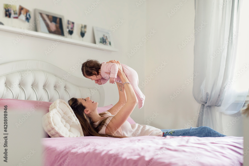 Mother playing with baby girl in bed Mother playing with baby girl in bed