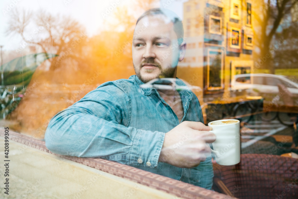 Man in cafe looking out of glass window Man in cafe looking out of glass window