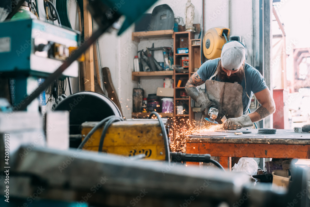 Axe maker using steel grinder in workshop Axe maker using steel grinder in workshop