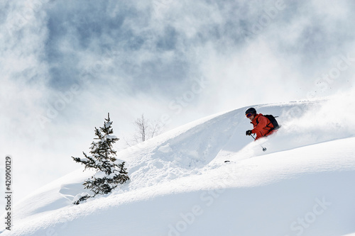 Male skier skiing down snow covered mountain, Alpe-d'Huez, Rhone-Alpes, France