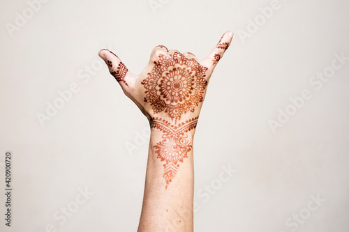Hand with henna tattoo making gesture