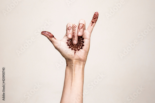 Hand with henna tattoo making gesture