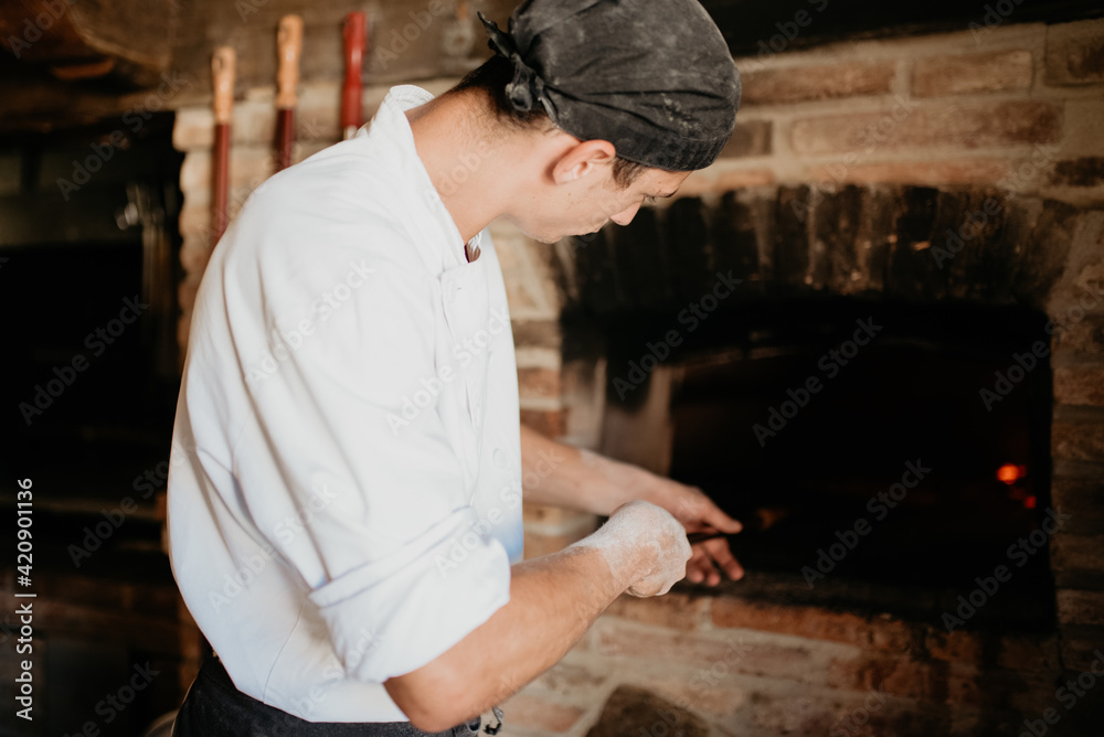Chef placing pizza into stone oven