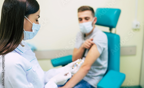 The doctor in the medical mask is preparing for man vaccination shot, medicine, and drug concept.