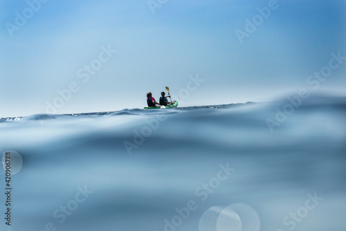 Teenage boy and mother sea kayaking, surface level distant view, Limnos, Khios, Greece