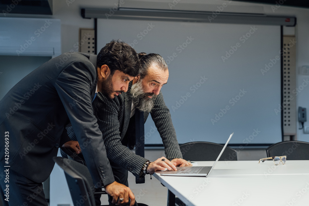 Business partners using laptop in office Business partners using laptop in office