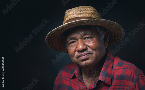 Portrait elderly Asian man wearing a hat smile and looking at camera on black background in the studio.