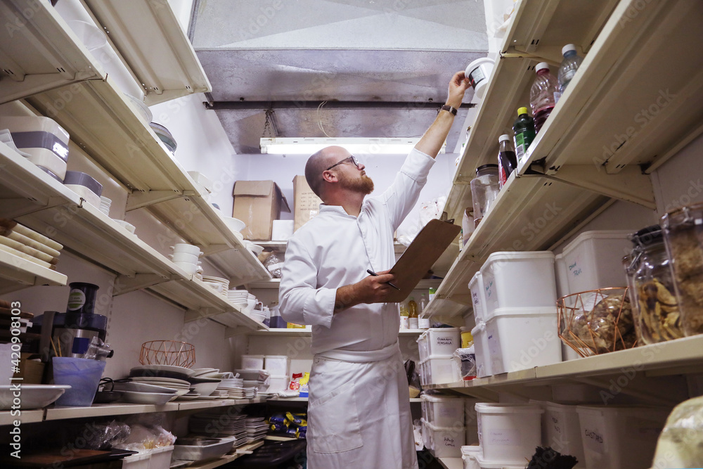 Chef checking stock of goods in storage room Chef checking stock of goods in storage room