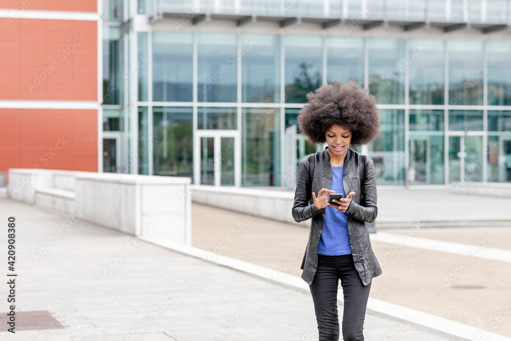 Young woman with afro hair in city, using smartphone touchscreen Young woman with afro hair in city, using smartphone touchscreen