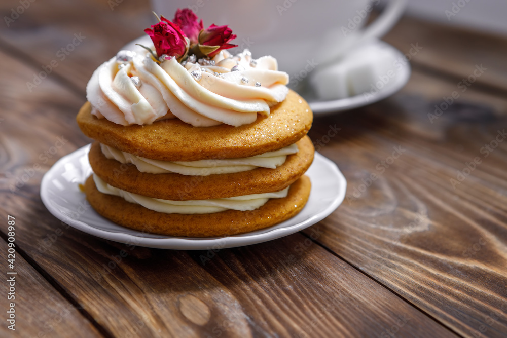 Sponge cake with cream, decorated with small flowers and a cup of tea. Sponge cake with cream, decorated with small flowers and a cup of tea.
