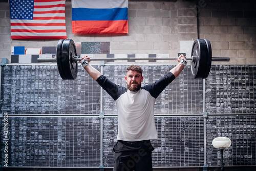 Young man lifting barbell in gym