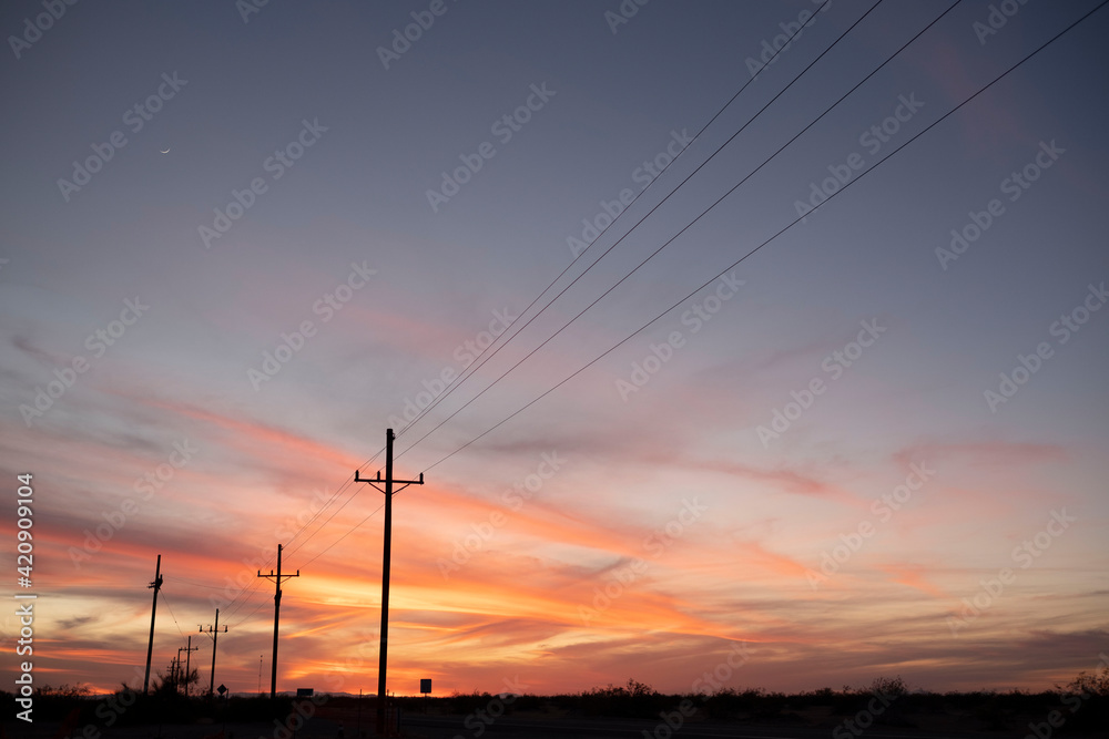 Sunset over highway lined with telephone poles Sunset over highway lined with telephone poles