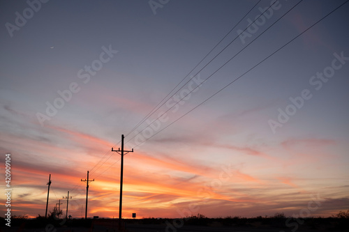 Sunset over highway lined with telephone poles