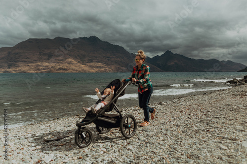 Mother with baby in pram walking on beach, Queenstown, Canterbury, New Zealand