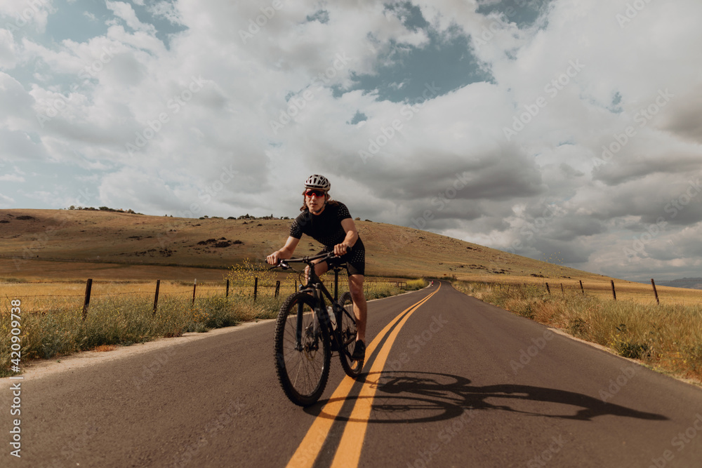 Young male cyclist cycling on rural road, Exeter, California, USA Young male cyclist cycling on rural road, Exeter, California, USA