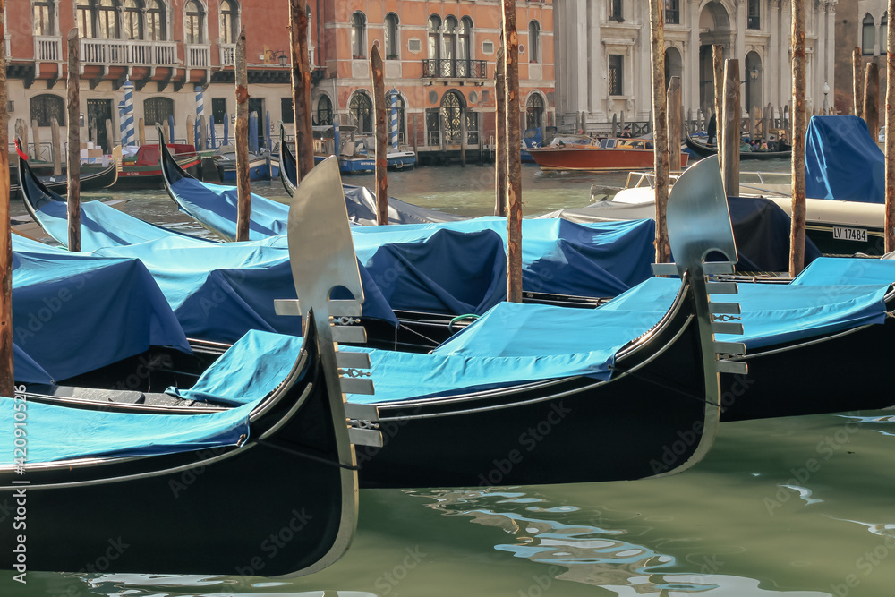 Gondolas parked on the Grand Canal near the Rialto Bridge in Venice, Italy. Travel concept.