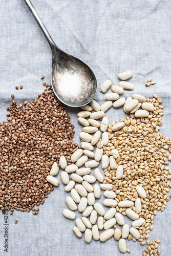 Still life of dessert spoon with lima beans, pearl barley and hemp seeds, overhead view