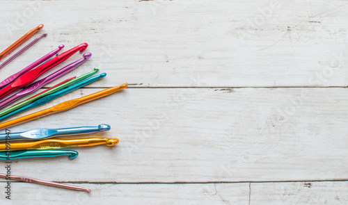 Colorful  crocheting hooks of different sizes on a wooden background with copy space