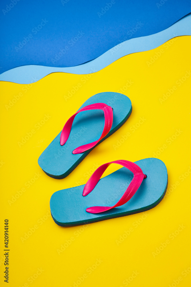Pair of colourful flip-flops on sandy beach by sea Pair of colourful flip-flops on sandy beach by sea